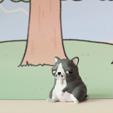 A small gray and white cartoon cat figurine from the Godgwawa — Weird Animals Blind Box by Partner Toys sits upright with a sleepy look, posed in front of a simple illustrated tree background.