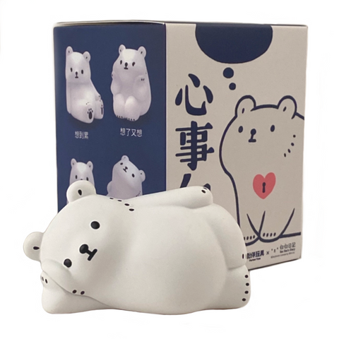 A figurine of a polar bear from the "Bac Bac is Thinking About (Polar Bear) Blind Box" by Partner Toys (TW) reclines in front of a box decorated with illustrations of polar bears, capturing the whimsical essence of blind boxes.