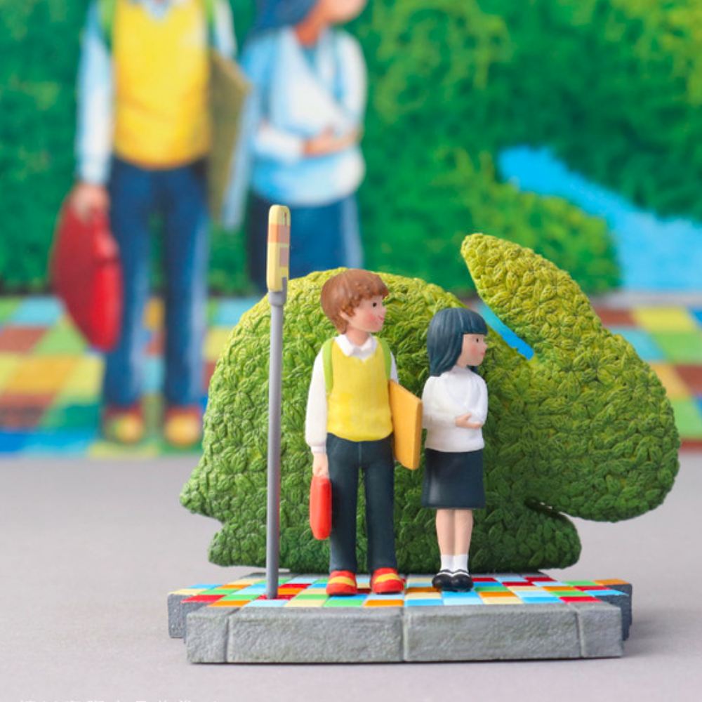 Two small figurines from the Partner Toys (TW) Starry Night Blind Box are displayed on a colorful platform before a green rabbit-shaped shrub, with a blurred mural in the background.