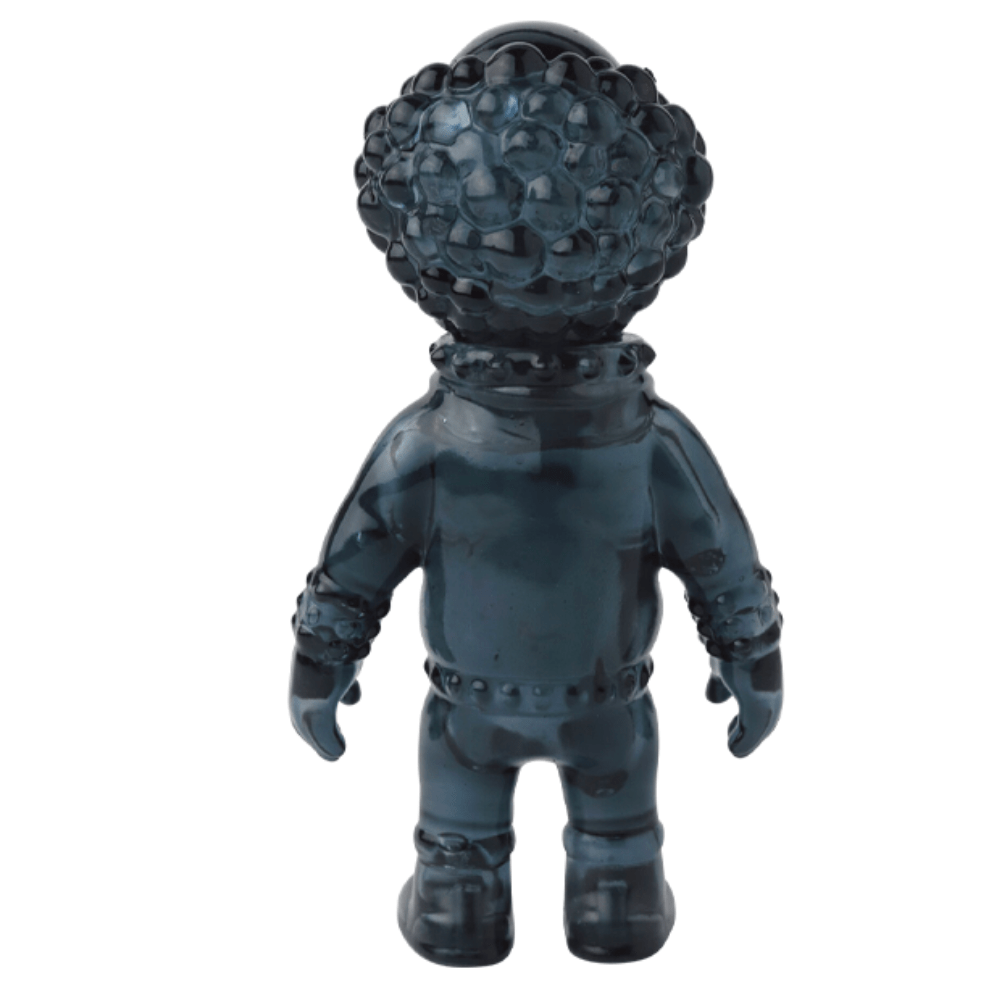 A dark, textured figure with a large, round head covered in bumps, viewed from behind. The humanoid shape resembles one of those quirky Japanese vinyl toy designs and is wearing a suit with boots. This unique piece could easily be mistaken for the VAG 36 - Deadman by Medicom (JP).