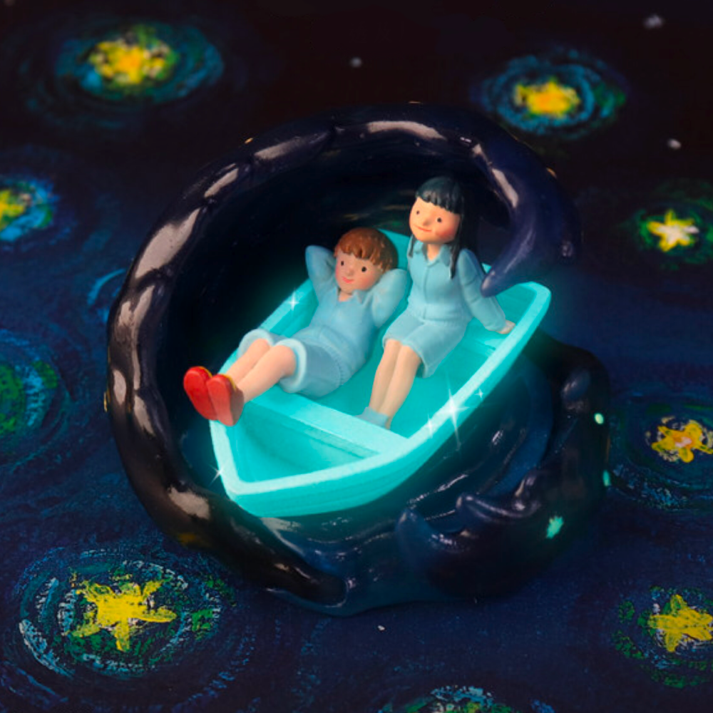 Two small figurines in pajamas lie in a glowing blue boat surrounded by a dark star-patterned wave—a wish come true, straight from the magic of the Starry Night Blind Box by Partner Toys (TW).