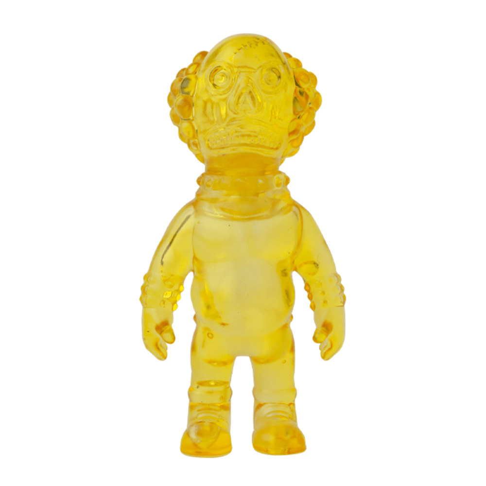 A small yellow translucent Medicom (JP) VAG 36 - Deadman figure with a large head, detailed facial features, and footwear, standing upright.