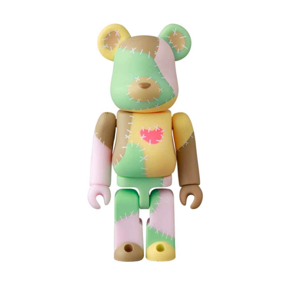 The Be@rbrick Series 50 Blind Box by Medicom (JP) features a toy bear figure with pastel green, pink, yellow, and brown patchwork, stitched details, and a pink heart on its chest—an ideal addition to any Bearbricks collection.