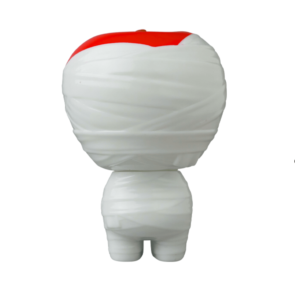 A small, white, mummy-like figurine with a red section on the top of its head seen from the back, resembling one of those unique gachapon figures or an exclusive Japanese vinyl toy like the VAG 36 - Yummy Mummy by Medicom (JP).