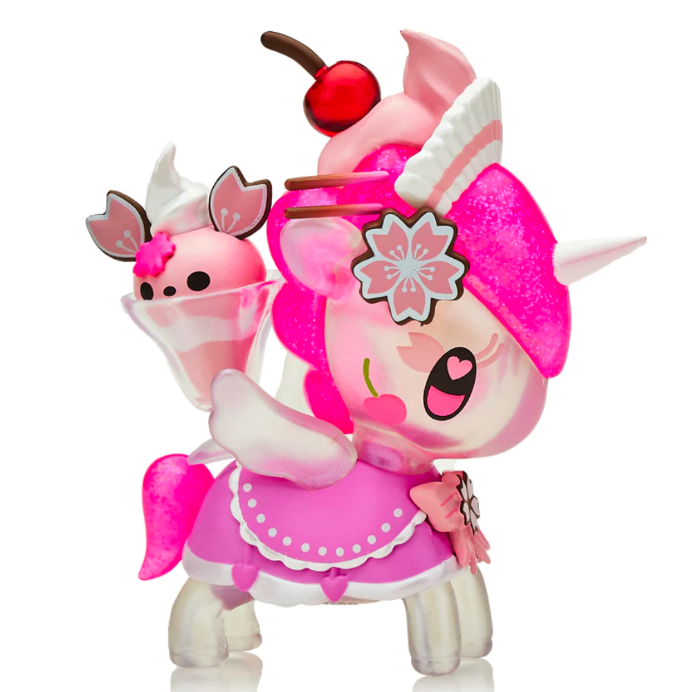 Introducing the Café Cuties Unicorno - Cherry Blossom (Special Edition) by Tokidoki: a whimsical pink and white unicorn figurine adorned with cherry-themed details, featuring delicate wings, a charming cherry on its head, and a cute bat-like creature perched on its back. This special edition blends charm and fantasy perfectly.