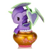 A Tokidoki Botanical Unicorno - Piantina (Special Edition) with a green horn, perched on a golden vase adorned with pink floral patterns. The unicorn, part of the tokidoki (IT) Special Edition, is shaded by green and purple heart-shaped leaves reminiscent of the distinctive Coleus plant.