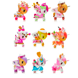 Nine vibrant unicorn figurines from the Tokidoki Cafe Cuties Blind Box collection are decorated with dessert-themed embellishments, including ice cream, donuts, and fruit. Displayed in a grid pattern of three rows with three figures each, these Tokidoki collectibles add a delightful charm to any collection.