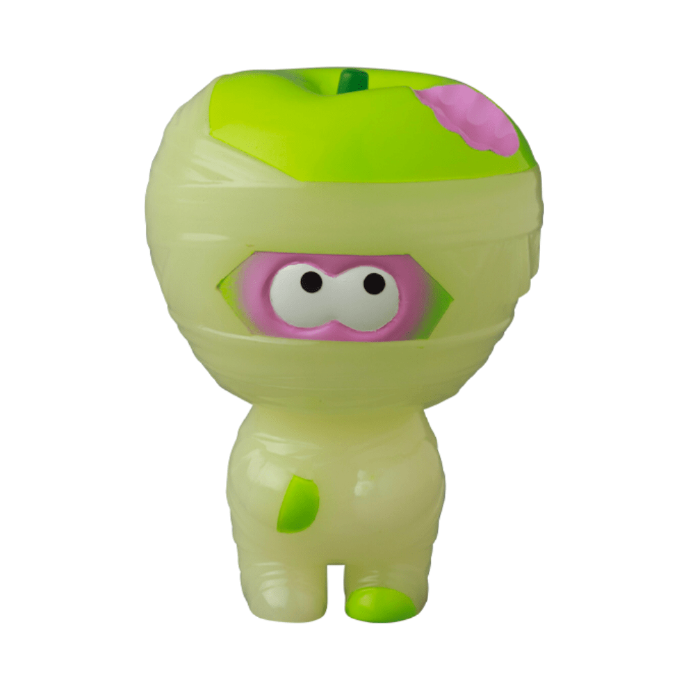 A small Medicom (JP) VAG 36 - Yummy Mummy toy resembling a mummy with bright green wrappings and a pink face, standing upright with wide, cartoonish eyes.