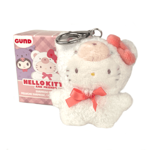 A small Hello Kitty plush keychain in a bear costume with a pink bow and ribbon is displayed in front of the GUND Hello Kitty & Friends Café Latte Blind Box.
