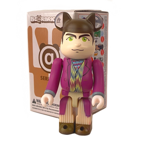 A collectible figurine from the Medicom Bearbrick Series 47 Blind Box dressed in a suit with cat-ear details, displayed in front of its packaging.