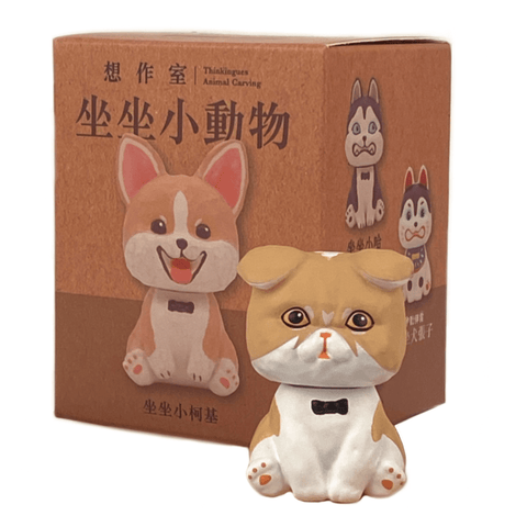 A small figurine of a brown and white dog with a black bowtie, from the Sitting Animals - Blind Box collection by Partner Toys (TW), in front of its packaging featuring illustrations of similar cartoon dogs.