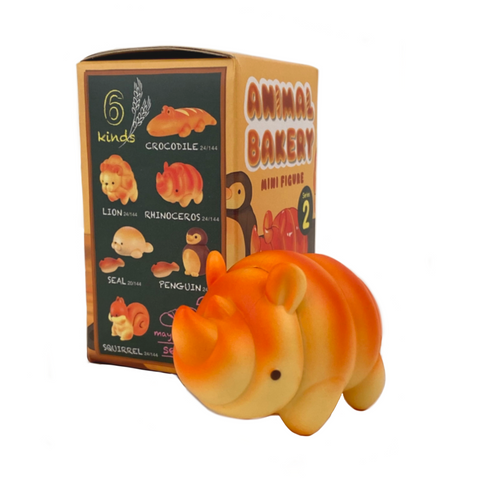 An orange rhino-shaped toy stands before an "Animal Bakery Series 2 Blind Box" by Dreams, featuring six charming animal designs, including whimsically cute bread-shaped figures like a lion, seal, and squirrel.