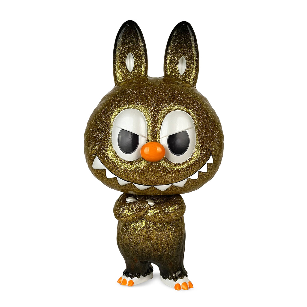 The Cowawa — Gold by How2Work (HK) is a glittery, rabbit-like figurine with large ears, big eyes, sharp teeth, an orange nose, and crossed arms, standing on two legs against a white background.