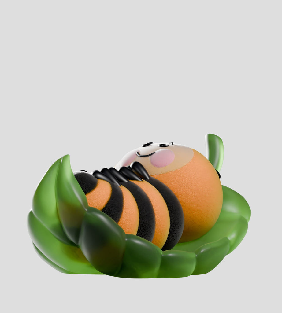 The Wooly Bear and Friends Vinyl Blind Box by Kaleidos Creative features a cute, round bee figurine with black stripes lying on its back in a green leaf cradle, displayed against a light gray background.