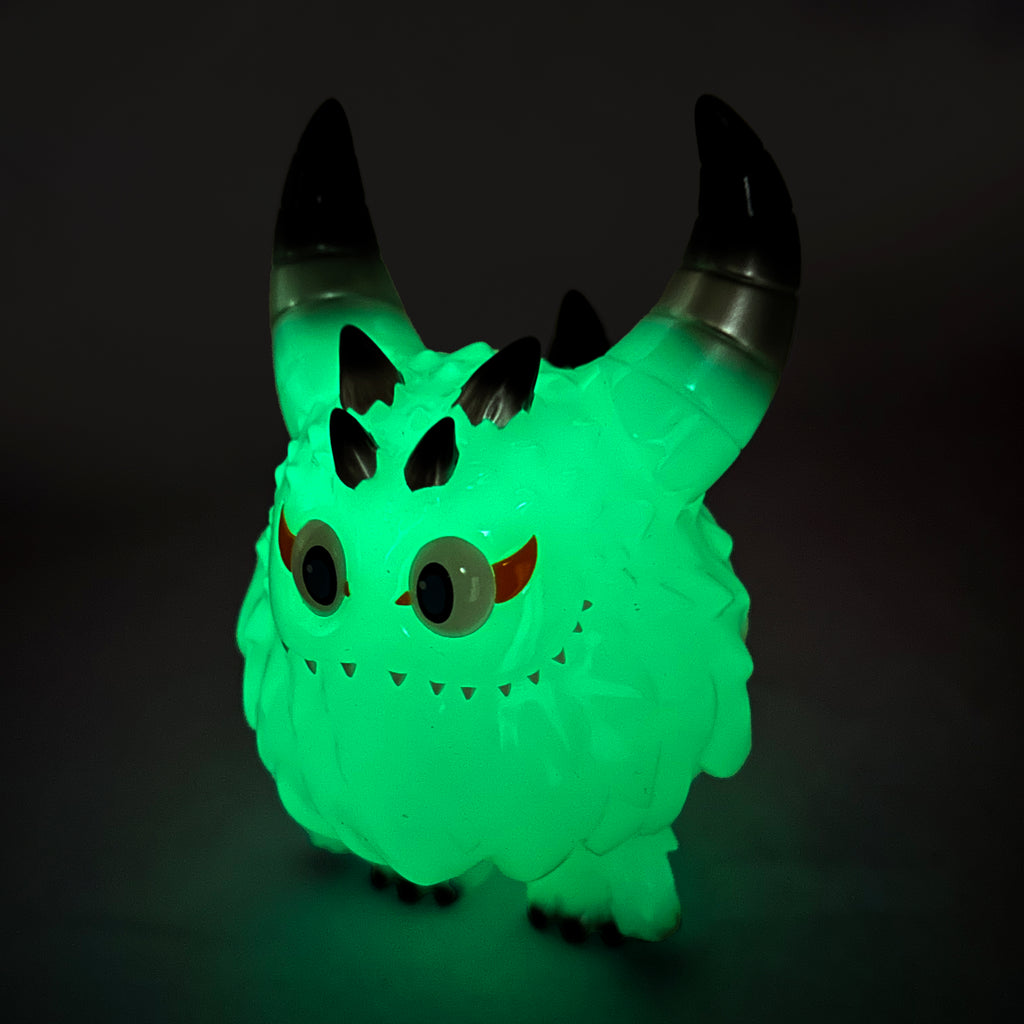 The Rangeas Rex Jr. — Glow by The Little Hut (HK) is a small figure with a woolly texture, big eyes, dark curved horns, and a playful monster-like appearance set against a dark background.