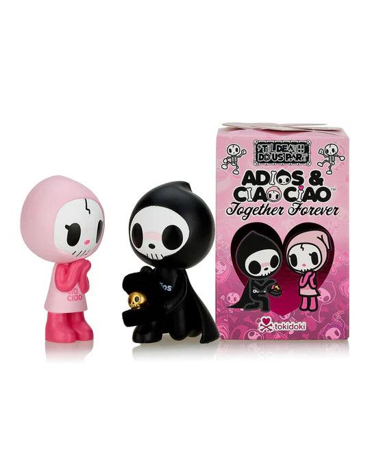 Two cartoon figurines, one in a pink outfit and the other in a black outfit, stand next to a pink box labeled 