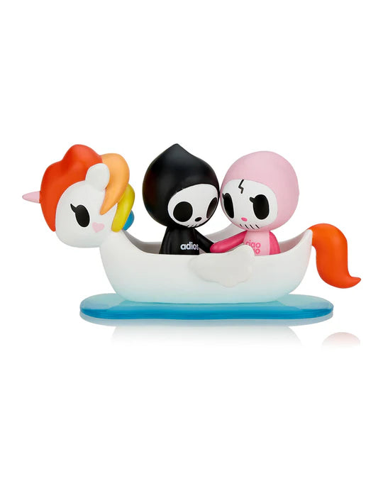 Two small figurines, Adios & Ciao Ciao from the tokidoki brand, featuring skull-like faces—one in black and the other in pink—sit in a white unicorn-shaped boat on a blue base. The Tokidoki Adios & Ciao Ciao Together Forever Blind Box is perfect for fans of the Blind Box Series or anyone looking to add a touch of whimsical love to their collection.