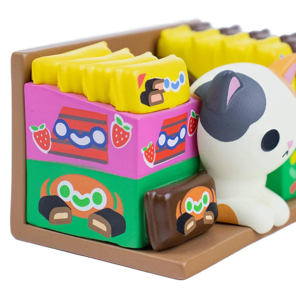 Show off your love for random collectibles with 100% Soft’s Bodega Kitties — Series 1 Blind Box, featuring colorful cartoon-style boxes, a brown tray, and an adorable white cat figurine with gray spots.