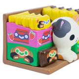 Show off your love for random collectibles with 100% Soft’s Bodega Kitties — Series 1 Blind Box, featuring colorful cartoon-style boxes, a brown tray, and an adorable white cat figurine with gray spots.