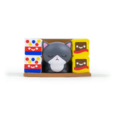 A small gray cat figurine with closed eyes from 100% Soft's Bodega Kitties — Series 1 Blind Box sits between colorful boxes featuring smiling faces.