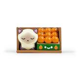 The Bodega Kitties — Series 1 Blind Box by 100% Soft features a cute sleeping cat figurine and cartoon oranges with faces, all arranged in a brown tray—perfect for discovering fun bodega-themed designs at random.