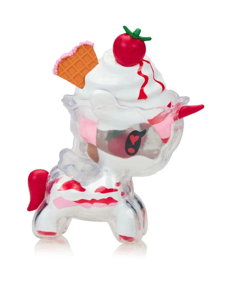A Tokidoki Ice Cream Shop Unicorno Blind Box figurine featuring a clear body, red accents, and topped with whipped cream, a cherry, and a waffle cone on its head.
