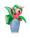 A pink Tokidoki Botanical Harmony Unicorno Blind Box figurine with green leaf wings sits in a blue marbled pot, viewed from the side on a white background—ideal for Tokidoki collectible fans.