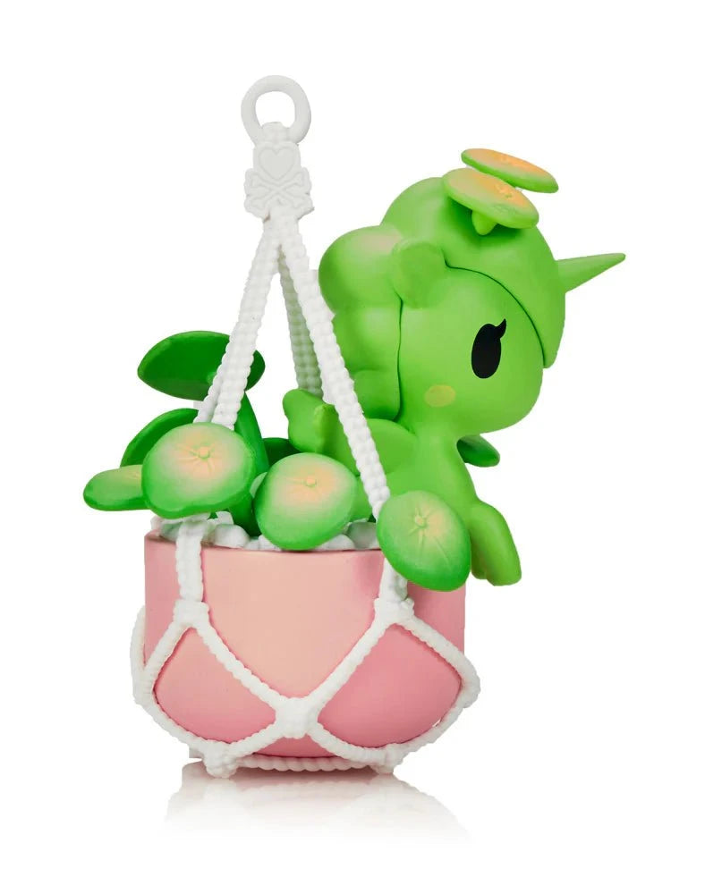 A small green Tokidoki Botanical Harmony Unicorno from the Blind Box series sits in a pink plant pot with leaf details, held by a white macrame hanger—a charming collectible for fans of Tokidoki and nature lovers.