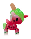 The Tokidoki Ice Cream Shop Unicorno Blind Box includes a red unicorn figurine with a green mane, heart-shaped markings, wings, and a popsicle stick on its back, designed to resemble a watermelon.