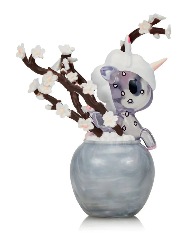 The Tokidoki Botanical Harmony Unicorno Blind Box features a ceramic unicorn figurine with cherry blossom branches in a round gray vase, celebrating nature's beauty.