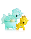 Two figurines from the Unicorno Capsule Cuties Blind Box by Tokidoki, featuring a translucent blue unicorn and a solid yellow unicorn with a crown, are positioned side by side. Fans of Tokidoki will adore these whimsical additions to their collection.