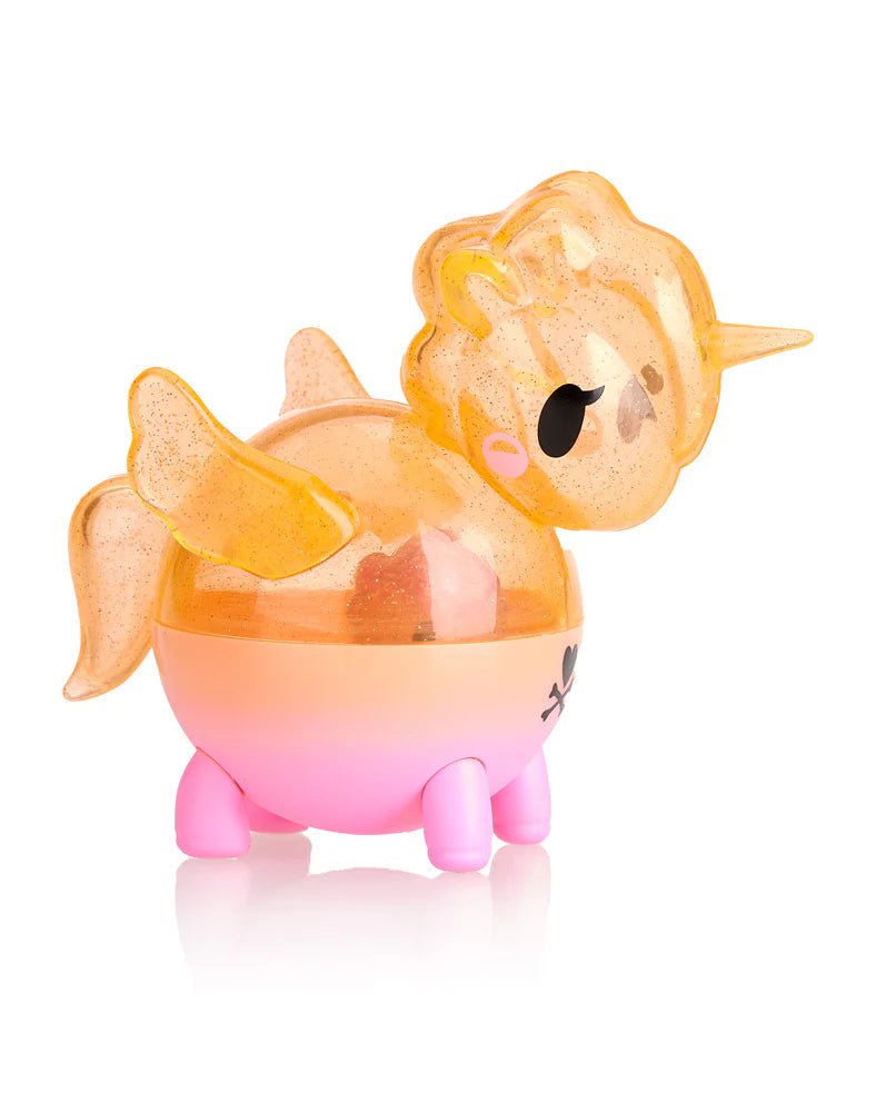 Introducing the Tokidoki Unicorno Capsule Cuties Pink Dusk Special Edition: a delightful unicorn toy featuring a rotund body, glittering translucent gold wings, and a sparkling horn. Its mane and tail are imbued with magical gleams, poised atop a pink base with petite legs—perfect for collectors and dreamers alike!