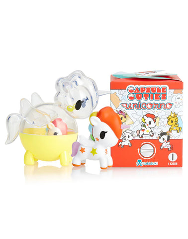 A toy unicorn figure stands beside a vibrant box labeled "Unicorno Capsule Cuties Blind Box," showcasing whimsical characters in classic Tokidoki style. This delightful blind box is perfect for fans of the enchanting Capsule Cuties collection.