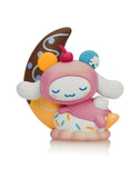 The Tokidoki x Cinnamoroll Sweet Treats Blind Box features a pastel Cinnamoroll figurine in a pink costume on a sprinkle-topped dessert base, leaning against a swirled crescent moon—part of Tokidoki's whimsical series.