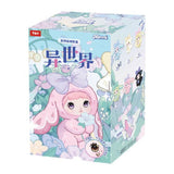 A Nommi Fantasy World Plush blind box featuring a cartoon illustration of a character with large eyes wearing a pink bunny-ear hood, with smaller plush designs displayed on the side.