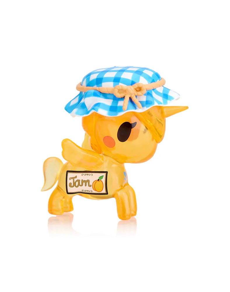 Unveil the magical Toki Mochi Donut Unicorno Blind Bag from Tokidoki, featuring a charming yellow unicorn figurine topped with a blue checkered hat and displaying a 