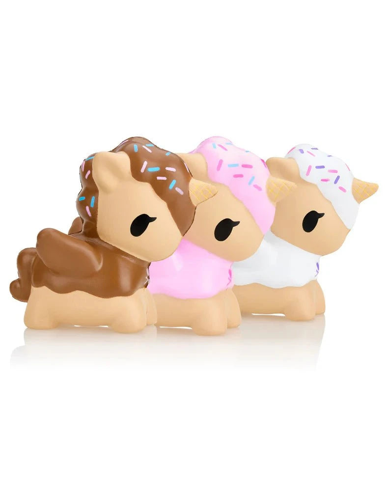 Three Toki Mochi Donut Unicorno Blind Bag toys by Tokidoki, each in small size with donut-themed designs and featuring chocolate, strawberry, and vanilla colors, are aligned side by side.