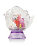 A clear plastic container shaped like a unicorn with a purple base, resembling the enchanting Tokidoki Dreaming Unicorno Blind Box from tokidoki, holds small figurines inside, including a unicorn, rainbow, and pink structures. Embark on a magical adventure with each charming piece.