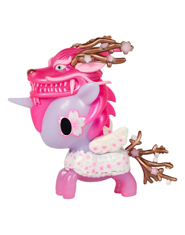 The Tokidoki Cherry Dragon Unicorno by Tokidoki is a pink and purple figure featuring wings, floral patterns, and a dragon-shaped headpiece with cherry blossoms and delicate branches.