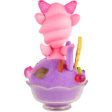A special edition Shaved Ice Dreams Unicorno Honey Bunny figure by tokidoki, featuring pink, cartoonish horns, sits in a glass bowl of purple shaved ice dessert topped with colorful decorations, viewed from behind.