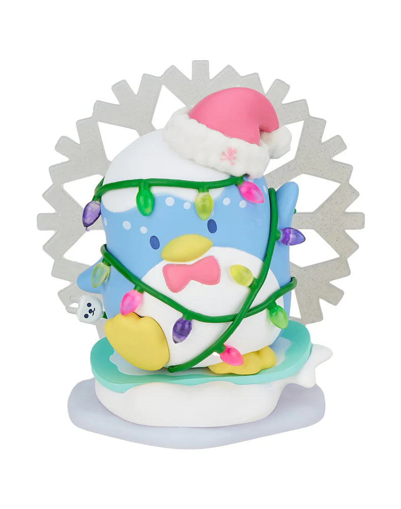 A blue penguin figure, adorned with vibrant lights, wearing a pink Santa hat and a white bow tie, joyfully stands before a snowflake backdrop. It's as if it has leaped from the Tokidoki x Hello Kitty and Friends Winter Dreams Blind Box, bringing the tokidoki magic to life.