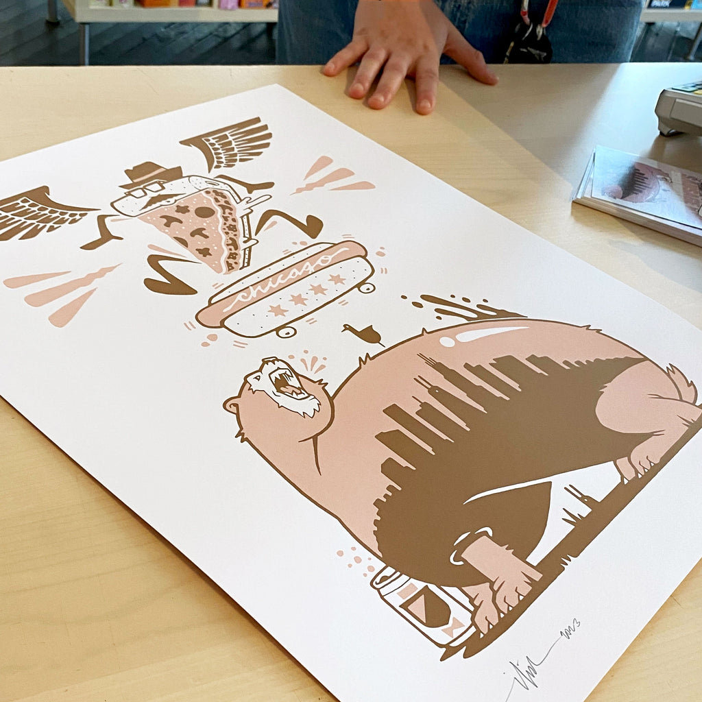 A person is admiring an Abe Froman Sausage King Screen Print by Jeremy Fish of a bear on a table wearing a t-shirt.