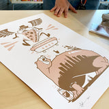 A person is admiring an Abe Froman Sausage King Screen Print by Jeremy Fish of a bear on a table wearing a t-shirt.