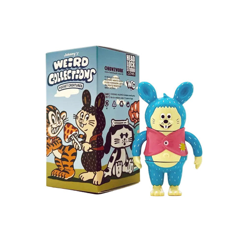 A blue and yellow bear-like vinyl figure with a pink cape stands beside the colorful Johnny's Weird Collection Pocket Creatures Blind Box by How2Work (HK), featuring whimsical designs from Johnny Akihito Noda’s series.