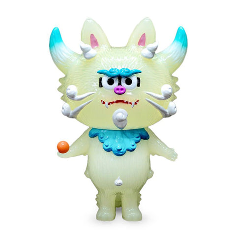 A toy figure resembling a mythical creature with white fur, blue accents, horns, and holding an orange ball is the Komataro — GID from The Little Hut (HK).