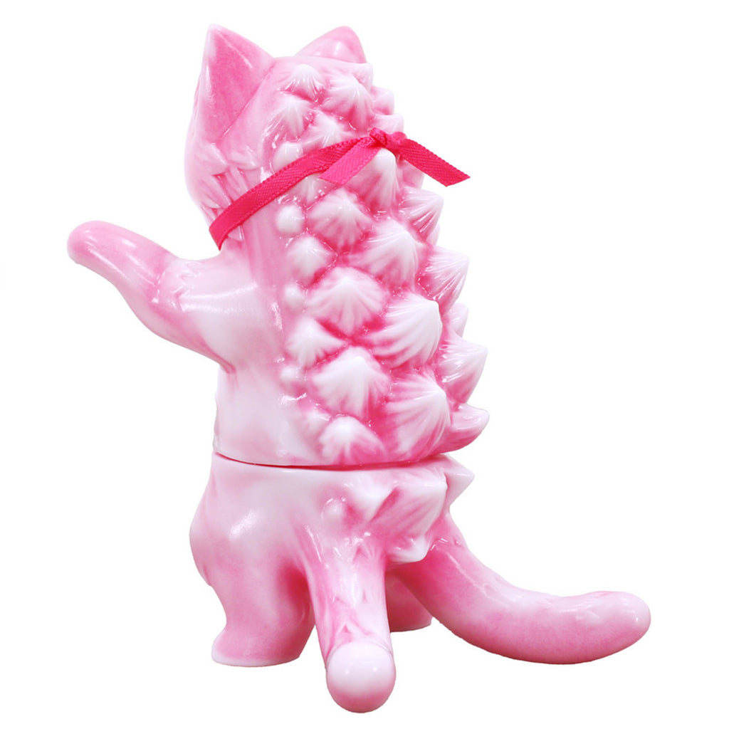 A pink, kitty cat-shaped figurine by a Japanese artist, featuring a textured, spikey back and a small red ribbon tied around its neck. This charming Negora — Strawberry Au Lait by Konatsuya (JP) is displayed from the rear.