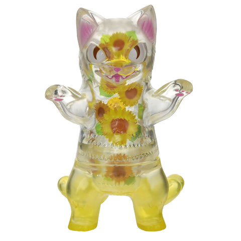 The Negora — Sunflower figure from Konatsuya (JP) is a clear plastic piece featuring a yellow base and adorned with sunflower designs on its belly and limbs. It stands upright with raised arms, inspired by the works of Japanese artist Konatsu.