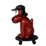The How 2 Work One-Chu Sk8 - Red Glitter is an eye-catching 8-inch collectible cartoon dog figure with a black cap, sitting on a black skateboard, featuring glittery red detail.