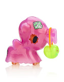 A pink stuffed animal from the tokidoki After Dark unicorno Series 4 - Blind Box with a green apple in its mouth.