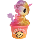 The Shaved Ice Dreams Unicorno Blind Box by tokidoki features a vibrant unicorn figurine with wings sitting in a pastel cup labeled “tokidoki” and adorned with a smiling sun logo, holding a translucent purple spoon—making it an ideal addition to any collectible toy or blind box collection.